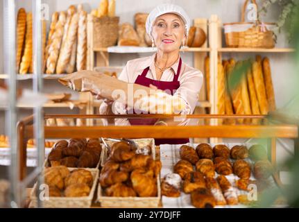 Un venditore di donne mature ha preso dalla finestra dei panini freschi di farina bianca Foto Stock