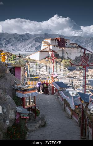 SHIGATSE, TIBET - 1 AGOSTO 2022: Ruote tibetane di preghiera o rotoli di preghiera dei fedeli buddisti e castello Shigatse, Tibet, Cina Foto Stock