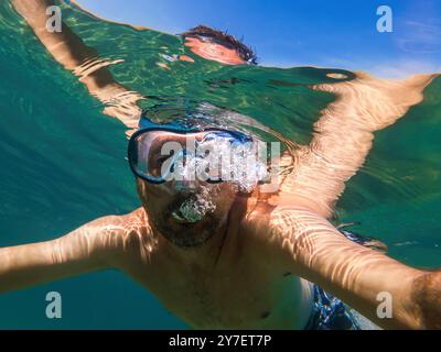 Uomo con maschera subacquea che nuota nell'oceano durante le vacanze estive, concentrazione selettiva Foto Stock