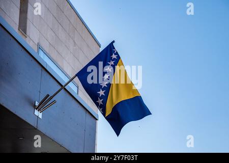Bosnische Flagge a Sarajevo 21.09.24, Sarajevo: Symbolfoto, Illustrationsbild, Symbolbild, Illustrationsfoto, Alltagsszene Bosnische Flagge in Sarajevo die Flagge von Bosnien und Herzegowina weht an einem Gebäude in Sarajevo gegen einen klaren, blauen Himmel. Die gelben und blauen Farben sowie die Weißen Sterne stehen im starken Kontrast zu der modernen Architektur im Hintergrund. Sarajevo Bosnien-Herzegovina *** bandiera bosniaca a Sarajevo 21 09 24, foto simbolo Sarajevo, immagine illustrazione, immagine simbolo, foto illustrazione, scena quotidiana bandiera bosniaca a Sarajevo la bandiera della Bosnia e di Herze Foto Stock
