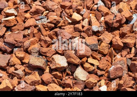 Piccoli pezzi di mattoni di argilla rossa o di mattoni rotti sullo sfondo. Questi trucioli, solitamente realizzati con mattoncini, vengono utilizzati nel processo di fusione durante la costruzione di svantaggi Foto Stock