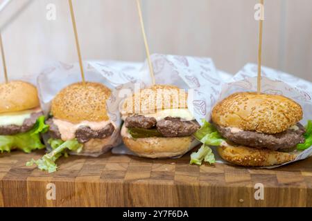 Quattro hamburger con stuzzicadenti. Gli hamburger sono su un tagliere di legno Foto Stock