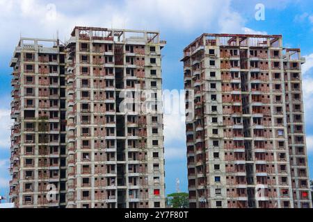 In costruzione edifici residenziali a torre gemellata con struttura in cemento o mattoni rossi, grande edificio multipiano in costruzione con uno splendido sfondo blu cielo Foto Stock
