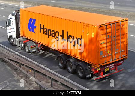 Container per trasporto intermodale con vista posteriore laterale Hapag-Lloyd su semirimorchio trainato da autocarro a motore principale hgv M25 strada autostradale Essex Inghilterra Regno Unito Foto Stock