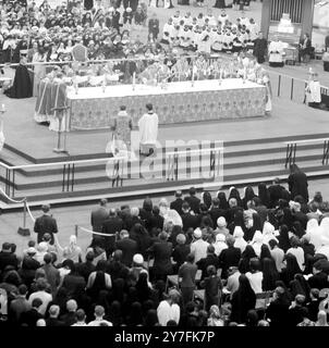 John Carmel , Cardinale Heenan, Arcivescovo di Westminster (Centre Elbow on altar table) concelebra l'alta messa insieme ad altri 12 sacerdoti all'interno della Exhibiton Hall della Corte dei conti di Londra. 29 giugno 1965 Foto Stock