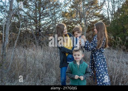 quattro fratelli in un abbigliamento casual giocano in un campo erboso e illuminato dal sole Foto Stock