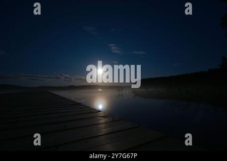 Luce di luna su un lago in Svezia in cui arriva un soggiorno di legno. Natura scandinava Foto Stock