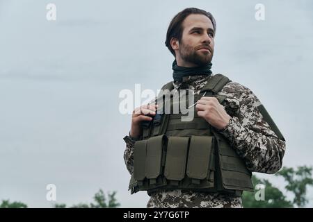 Giovane uomo premuroso in uniforme militare che guarda lontano mentre si trova all'aperto Foto Stock