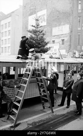 18 DICEMBRE 1964 i soldati alleati al posto di frontiera, Checkpoint Charlie, sono raffigurati per fissare un albero di Natale al tetto della baracca dei checkpoint a Friedrichstrasse, Berlino, Germania Ovest. Foto Stock