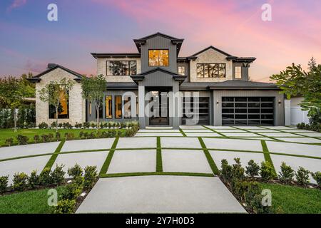 Casa moderna e lussuosa con un grande vialetto e un giardino splendidamente paesaggistico al tramonto Foto Stock