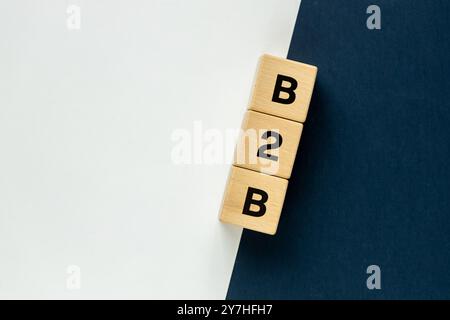 Simbolo business to business B2B su blocchi di legno con sfondo blu scuro e bianco. Icona della cooperazione. Transazioni commerciali e partnership aziendale Foto Stock