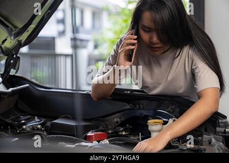 Una giovane donna chiede assistenza perché la sua auto si è rotta Foto Stock