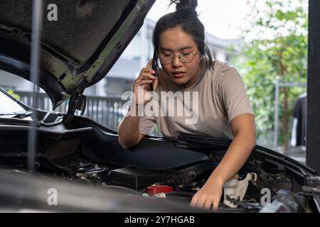 Una giovane donna chiede assistenza perché la sua auto si è rotta Foto Stock