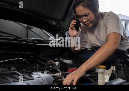 Una giovane donna chiede assistenza perché la sua auto si è rotta Foto Stock