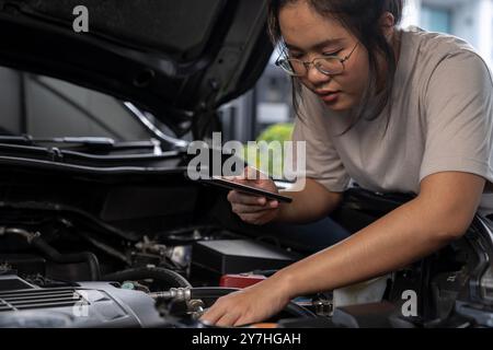 Una giovane donna chiede assistenza perché la sua auto si è rotta Foto Stock