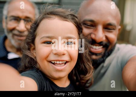 Ritratto ravvicinato di un ragazzo sorridente che scatta selfie con padre e nonno Foto Stock