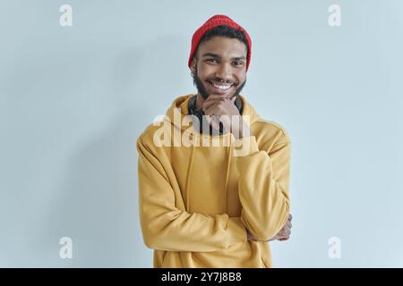 Bell'africano che tiene le braccia incrociate e sorride mentre si trova contro il muro Foto Stock