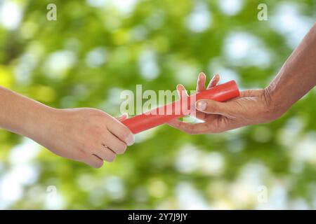 Uomo che passa il testimone per il compagno di squadra all'aperto, primo piano Foto Stock