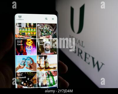 Persona che detiene un cellulare con pagina Web della società danese Royal Unibrew sullo schermo davanti al logo. Messa a fuoco al centro del display del telefono. Foto Stock