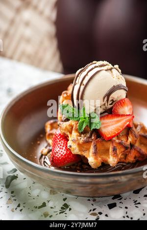 Waffle all'americana con gelato, fragole, sciroppo d'acero e gocce di cioccolato fondente. Foto Stock