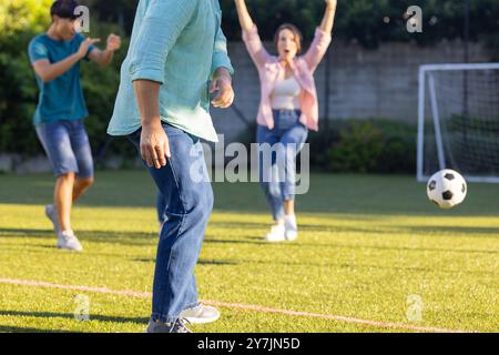 Giocando a calcio nel cortile posteriore, la famiglia si diverte a stare insieme all'aria aperta Foto Stock