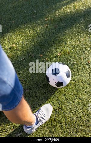 Calcio su erba, persona che indossa sneakers e pantaloncini denim Foto Stock