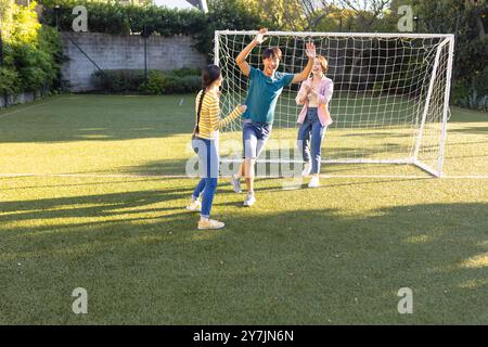 Giocando a calcio, la famiglia festeggia il gol sul campo con la rete nel cortile Foto Stock