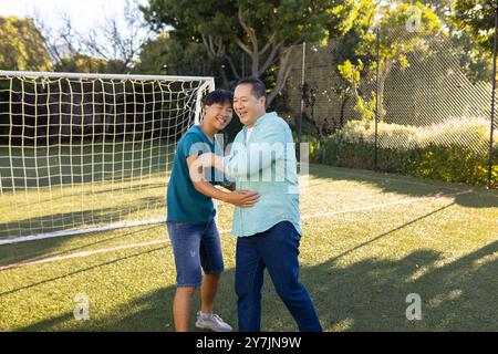 padre e figlio asiatici giocano insieme sul campo di calcio, godendosi il tempo libero Foto Stock