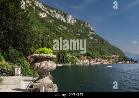 Affascinante villaggio di Varenna lungo il Lago di Como in Italia, annidato sotto le Montagne Rocciose con vegetazione. Il tranquillo lungomare di una vista pittoresca. Foto Stock