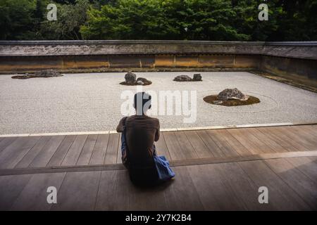 Un uomo medita nel giardino zen giapponese, il tempio Ryoan-Ji a Kyoto Foto Stock