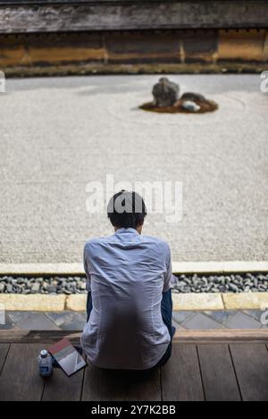 Un uomo medita nel giardino zen giapponese, il tempio Ryoan-Ji a Kyoto Foto Stock