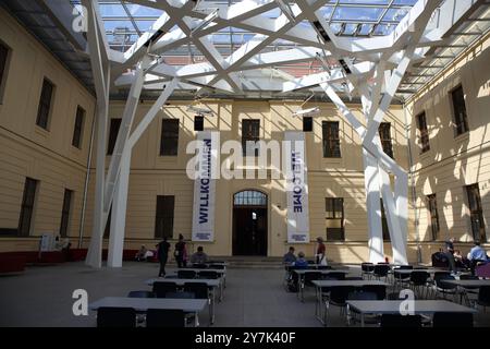 Cortile sul retro con persone sedute ai tavoli nell'edificio in stile barocco del Museo Ebraico di Berlino, è visibile una moderna struttura di supporto con un tetto in vetro. Foto Stock