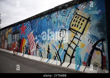 Graffiti raffiguranti questioni politiche, ambientali e sociali viste sul muro di Berlino costruito dai tedeschi dell'Est nel 1961 per circondare Berlino Ovest. Foto Stock