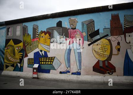 Graffiti raffiguranti questioni politiche, ambientali e sociali viste sul muro di Berlino costruito dai tedeschi dell'Est nel 1961 per circondare Berlino Ovest. Foto Stock