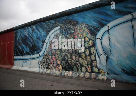 Graffiti raffiguranti questioni politiche, ambientali e sociali viste sul muro di Berlino costruito dai tedeschi dell'Est nel 1961 per circondare Berlino Ovest. Foto Stock