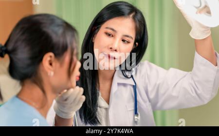 Donna professionale consulenza medica in clinica cosmetologica. Medico di bellezza professionista che parla con una ragazza piuttosto giovane. Foto Stock