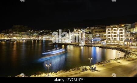 Porto notturno con edifici illuminati, luci riflesse nelle acque calme, Pigadia, la città e il porto, Pigadia Bay, la città principale, Karpathos, Dodecan Foto Stock