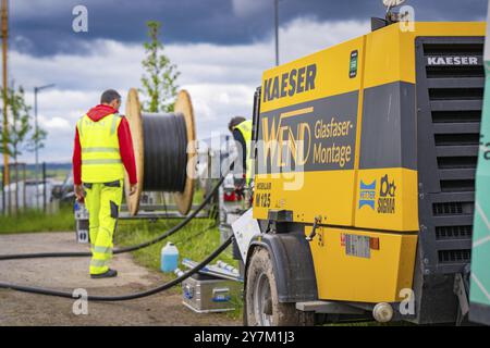 Un operaio edile lavora in un cantiere con un grande avvolgicavo e macchine all'aperto, installazione in fibra ottica, distretto di Calw, Black Fores Foto Stock