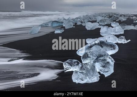 Banchi di ghiaccio, spiaggia, mare, onde, nuvoloso, Diamond Beach, Breidamerkursandur, Joekulsarlon, Islanda, Europa Foto Stock