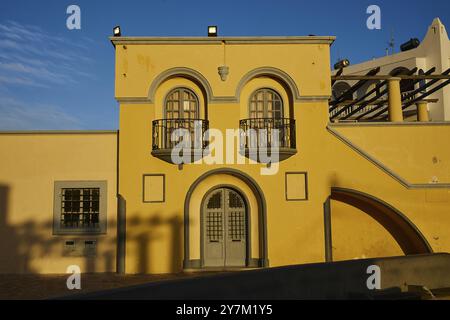 Edificio giallo con balconi decorativi e grandi finestre, illuminate dalla luce dell'ultima sera, il municipio, Dimarchio, Pigadia, la città e il porto, P Foto Stock