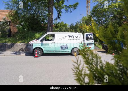 Un furgone aziendale con il logo aziendale parcheggiato sul ciglio della strada sotto un cielo blu accanto a alberi e coni stradali, installazione in fibra di vetro, distributore Calw Foto Stock