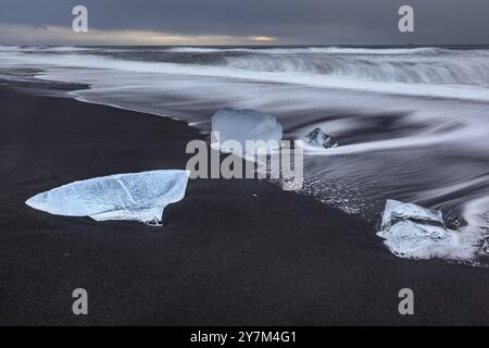 Banchi di ghiaccio, spiaggia, mare, onde, nuvoloso, Diamond Beach, Breidamerkursandur, Joekulsarlon, Islanda, Europa Foto Stock