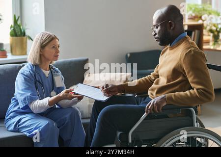 Black Man with Disability Signing Medical Form Foto Stock