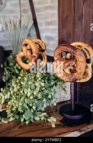 Pretzel bavaresi tradizionali esposti su bancarelle con luppolo fresco, Oktoberfest e cucina tedesca Foto Stock