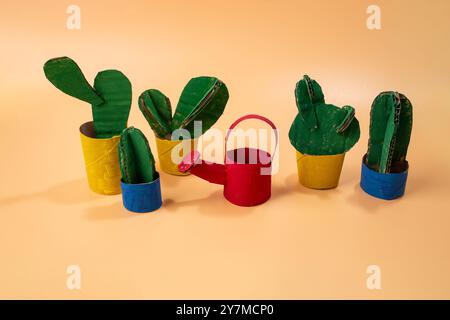 Gruppo di piante di cactus disposte su tela gialla. Design di giocattoli artistici concettuali. Foto del prodotto della lattina di abbeveratoio in cartone per bambini, fai da te, tutorial Foto Stock