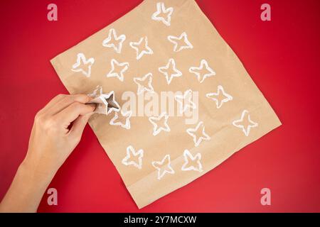 Come creare carta da imballaggio personalizzata, facile da realizzare per i bambini, carta marrone con motivi bianchi, rotolo di carta igienica piegato, nastro rosso, design esclusivo con trama, confezione regalo creativa per le feste Foto Stock