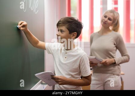 Scolaro che scrive sulla lavagna in classe Foto Stock