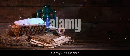 Manger con bambino, vecchio libro e lanterna su sfondo di legno con spazio per il testo. Concetto di storia di Natale Foto Stock