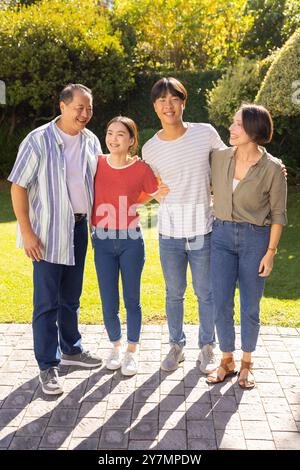 Una famiglia sorridente che si riunisce all'aperto, godendo del tempo di qualità in giardino Foto Stock