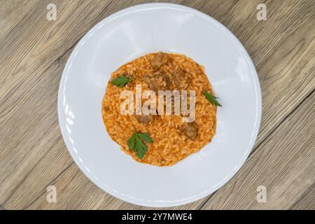 Vista dall'alto del risotto italiano servito con salsiccia e salsa di pomodoro su un letto di riso. Foto Stock